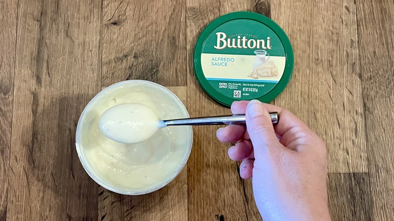 hand spooning Buitoni Alfredo Sauce