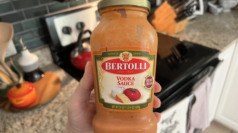 Hand holding jar of Bertolli Vodka Sauce