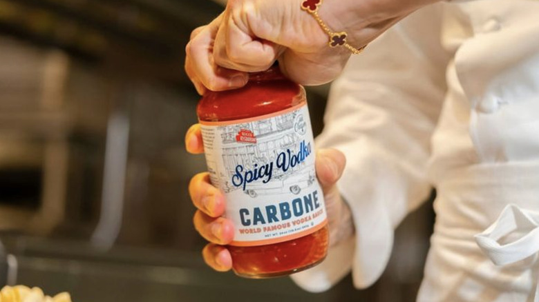 Chef opening jar of Carbone Spicy Vodka Sauce