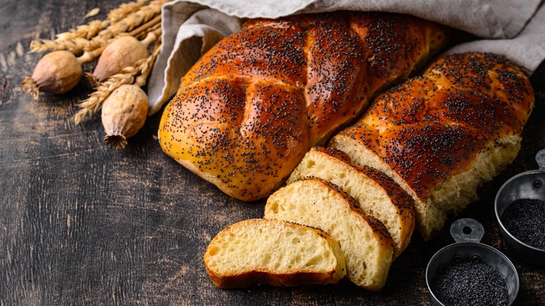 Traditional challah braided sweet bread topped with poppy seeds is sliced and ready to eat