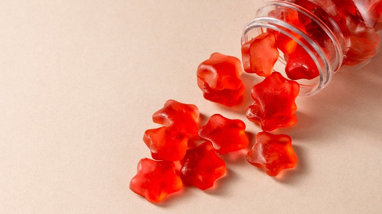 Red star-shaped gummy candies spilling out of clear jar