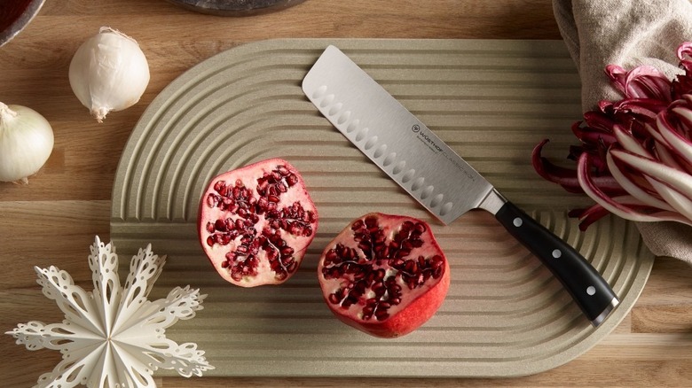 A nakiri knife next to pomegranate and garlic