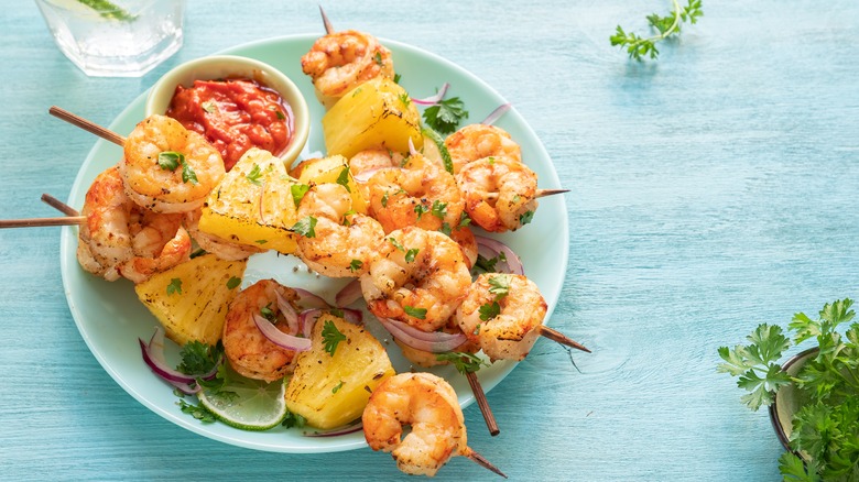 Dish of grilled shrimp and pineapple on wooden skewers