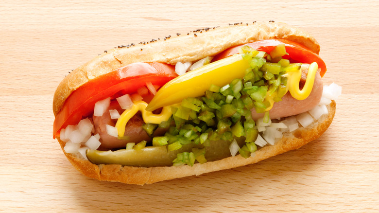 Hot dog with a pickle spear and other garnishes