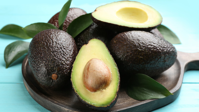 Whole and cut avocados on round board