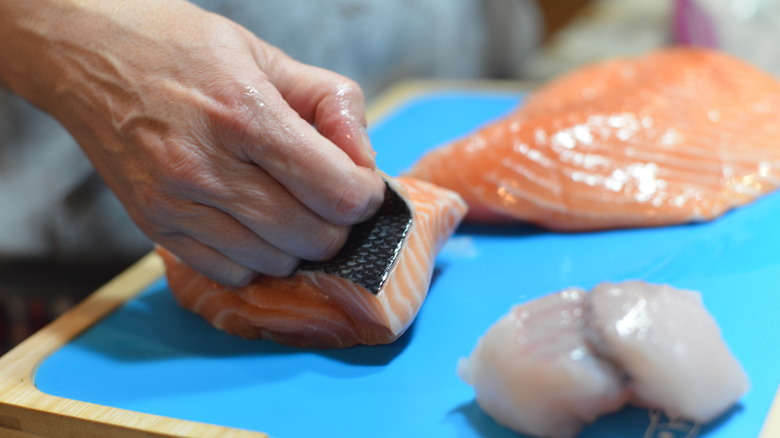 Chef peeling the skin off of a salmon filet