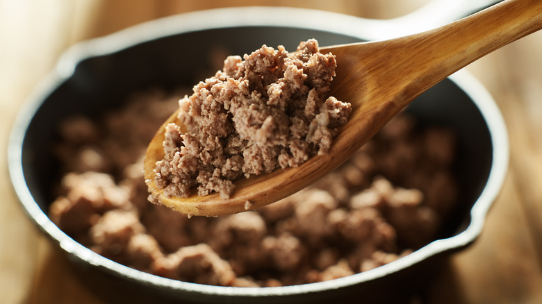 cooked ground beef on wooden spoon and in pan