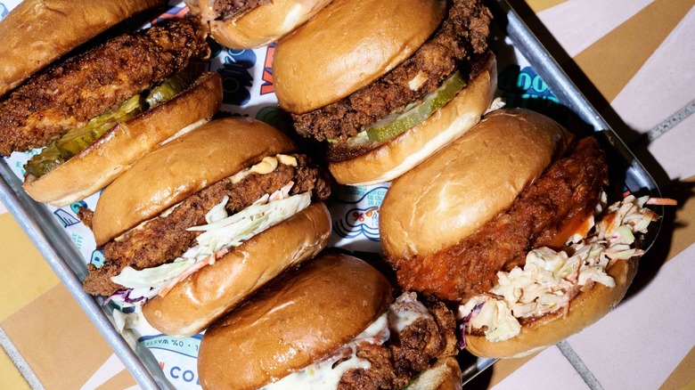 Various Birdcall chicken sandwiches lined up on a metal tray