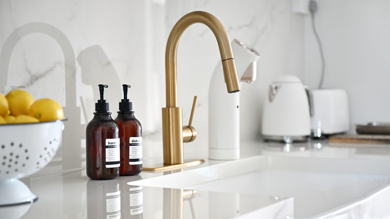 Closeup on a modern brass faucet in a white kitchen