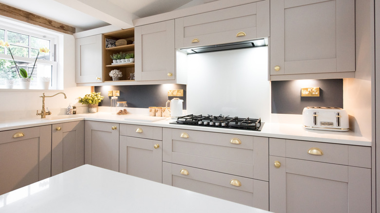 A modern kitchen with brass drawer and cabinet pulls and an old-fashioned brass faucet