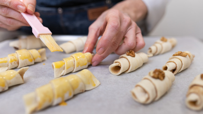 a person brushes a tray of rugelach with egg wash