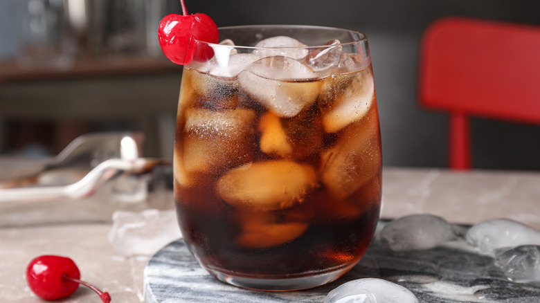 Nonalcoholic drink in glass with cola and maraschino cherries on ice