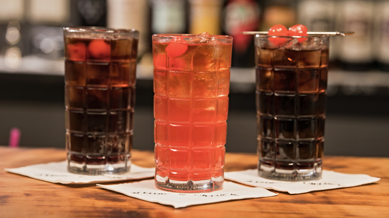 Soda cocktails in tall glasses with maraschino cherries on napkins in a bar