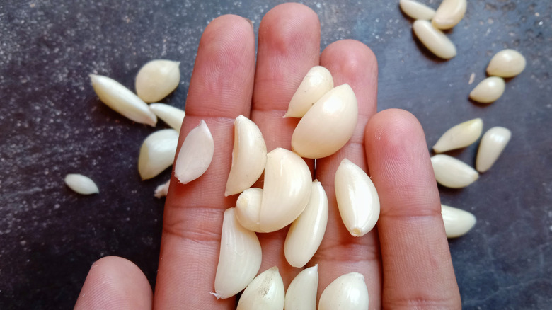 Open palm hand holding peeled garlic cloves 