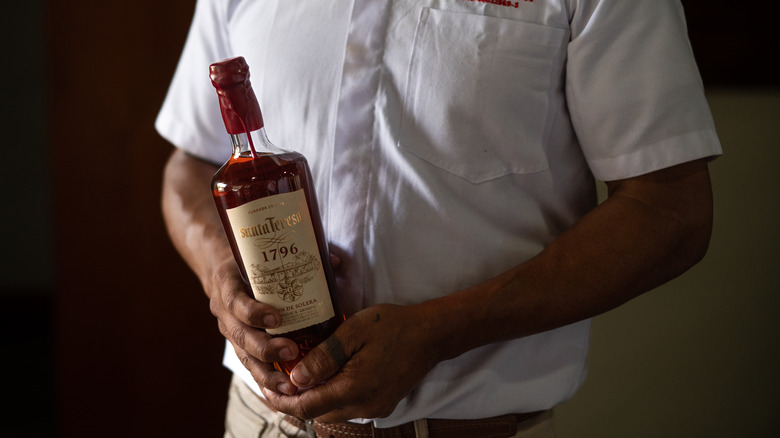 Man holding bottle of aged rum