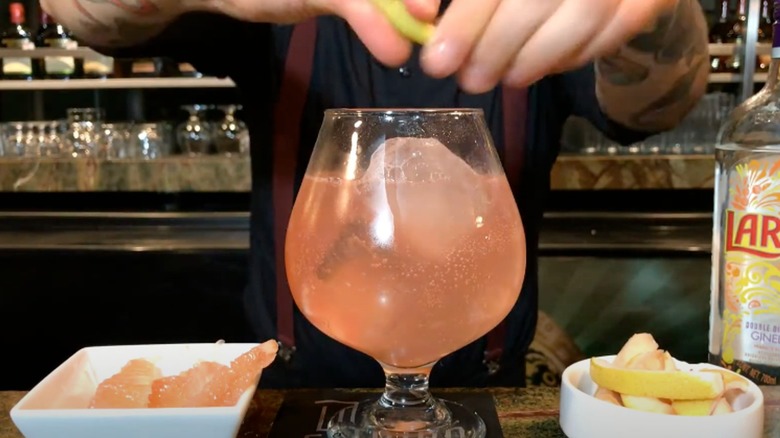 Pink Salmoncito cocktail in ice filled glass sits on a table