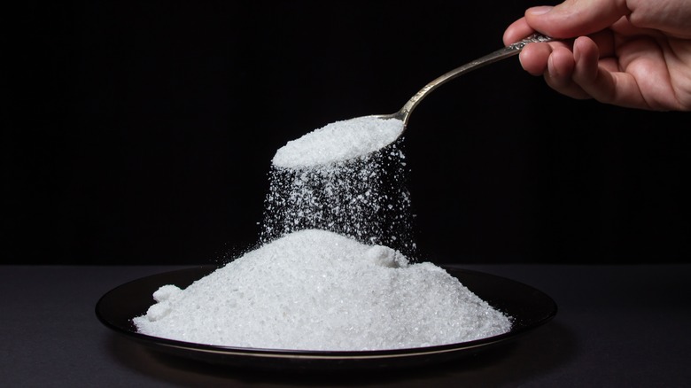 Person spooning salt from large pile 