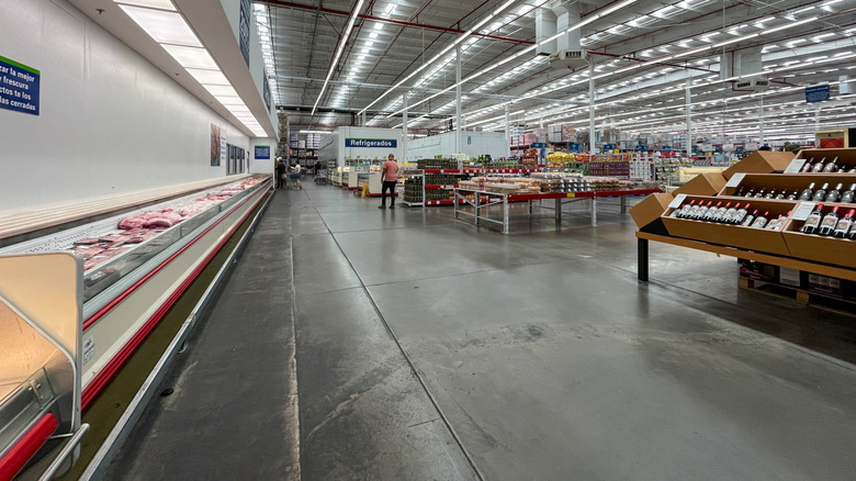 In an interior shot of a Sam's Club, a long cooler sits opposite an alcohol display