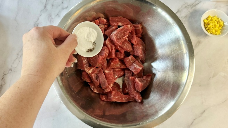 hand holding powder over meat