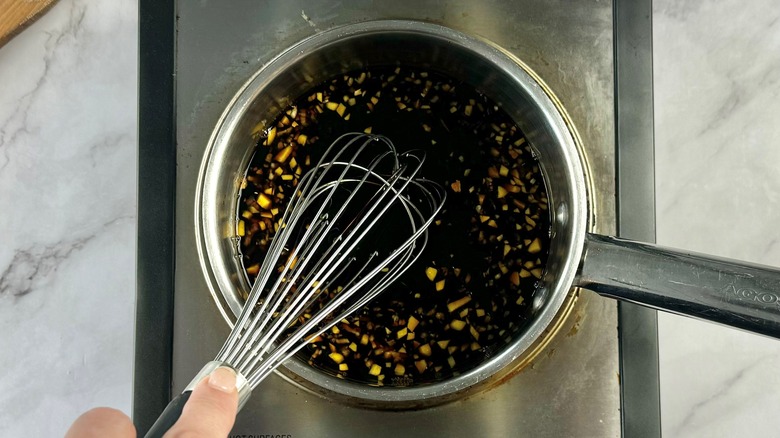 hand stirring teriyaki sauce