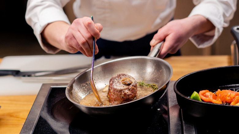 Chef searing steak and basting it with butter