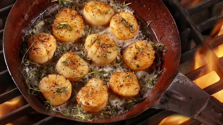 Seared scallops with rosemary and butter in a red pan