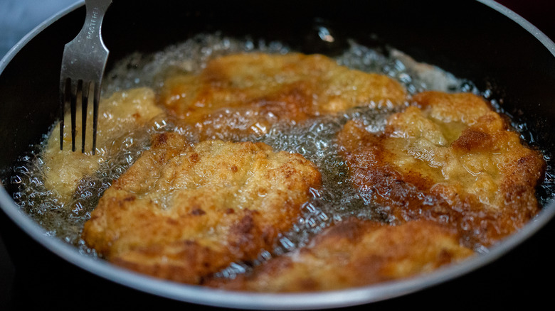 Pan-fried breaded chicken in a cast iron pan with a fork