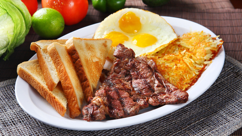 Steak eggs with hash browns and toast ona plate