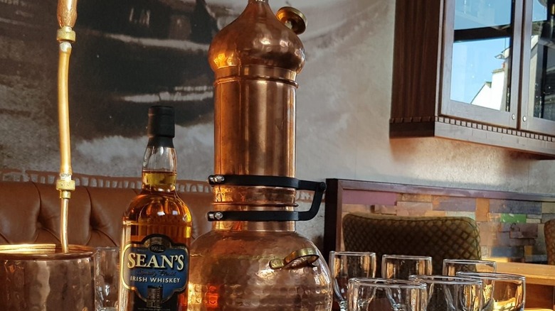 Bottle of Sean's Bar Irish Whiskey next to copper distiller