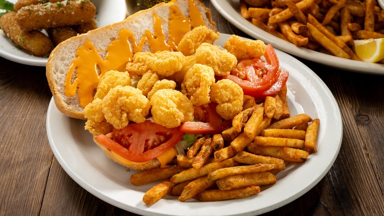 a po'boy and seasoned fries on a plate