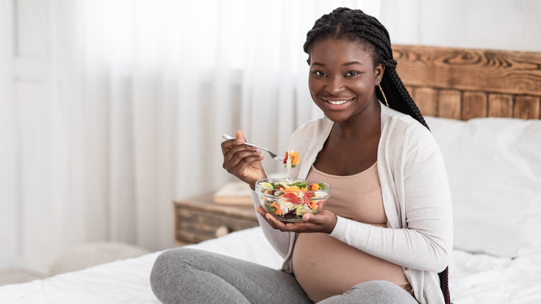 smiling pregnant woman eating salad