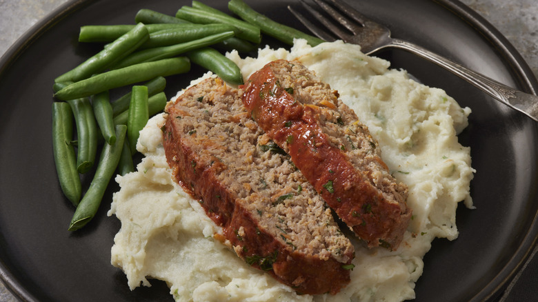 meatloaf on a bed of mashed potatoes with green beans