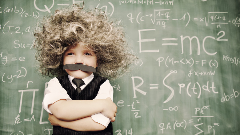 child in Einstein costume by chalkboard with equations