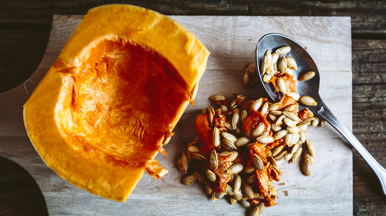 A hollowed out pumpkin next to its seeds and flesh