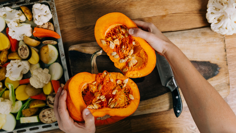 Person cutting a pumpkin in half