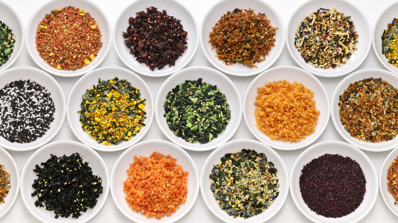 Organized lines of small white bowls filled with furikake varieties