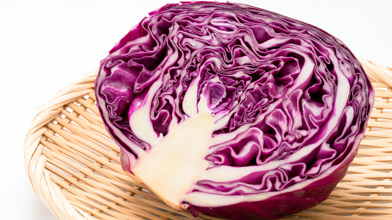 A purple cabbage cut in half sitting in a basket