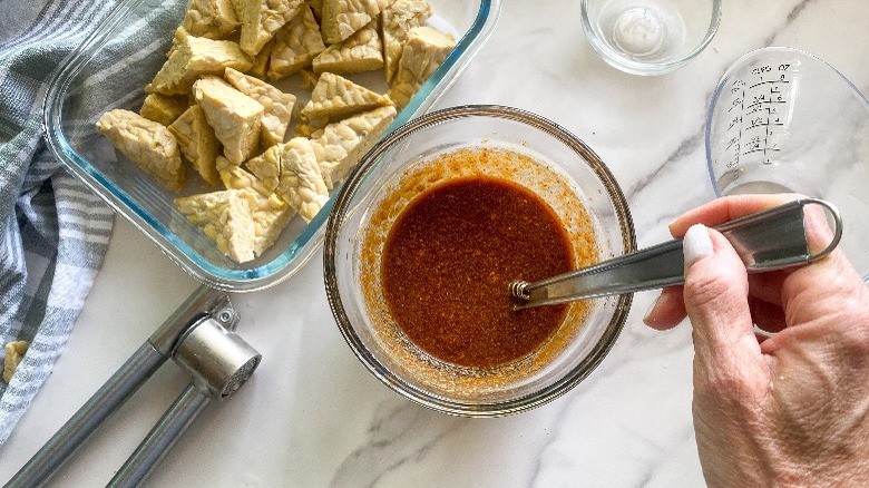 sauce in bowl next to tempeh in container