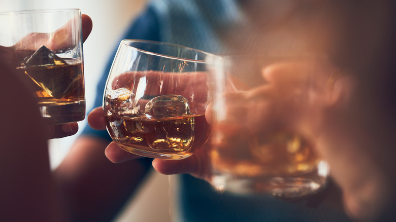 toasting whiskey in glasses with ice