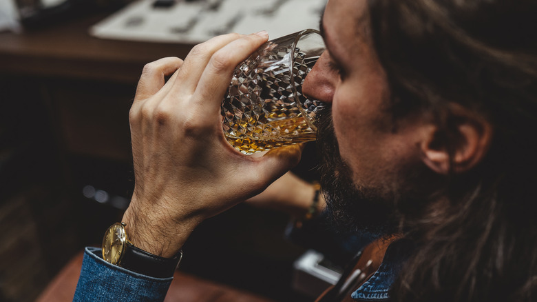 man drinking whisky from glass