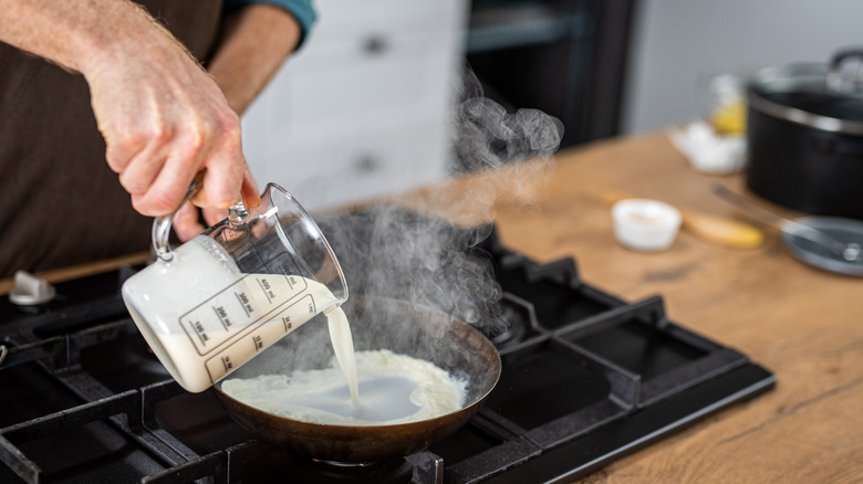 Pouring milk into pan on stove