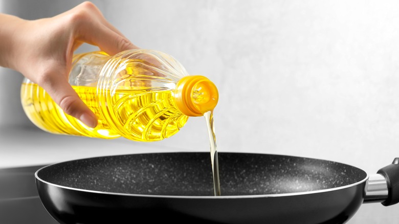 pouring olive oil into pan