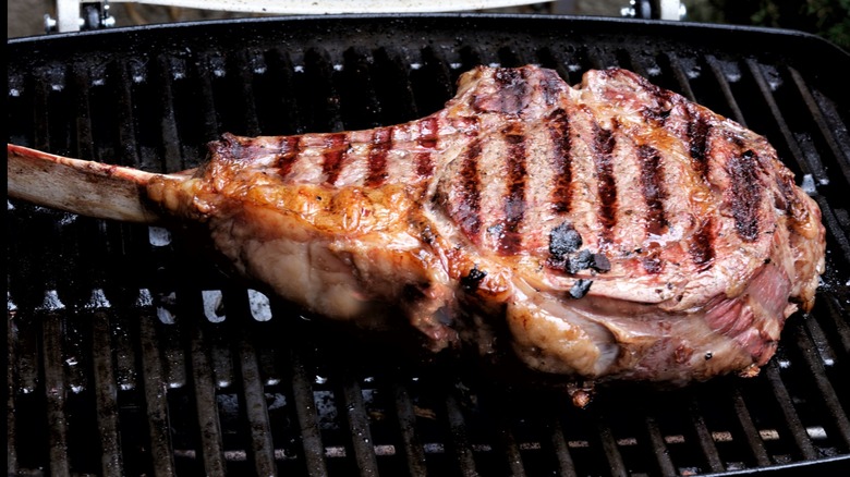 Tomahawk steak cooking on grill