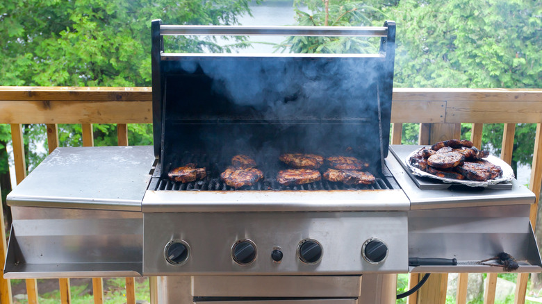 Pork steaks cooking on gas grill with open lid