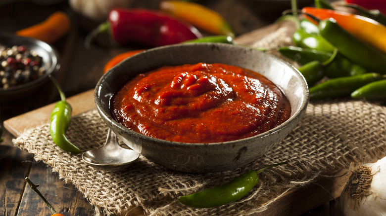 sriracha sauce displayed in black bowl alongside chili peppers