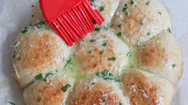 garlic butter brushing onto rolls