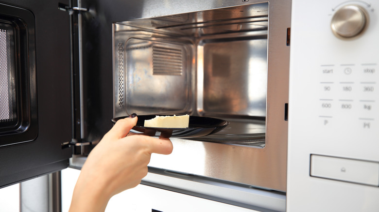 Hand placing butter in microwave