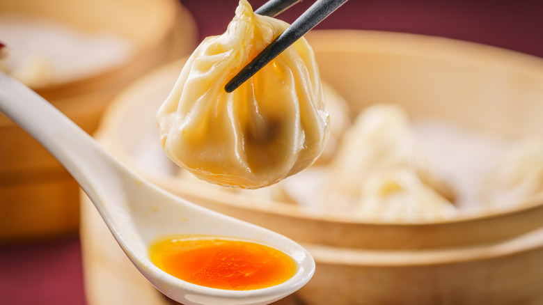 Chinese soup dumplings with a soup spoon and chopsticks.