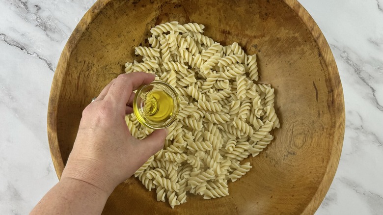 hand holding oil over pasta