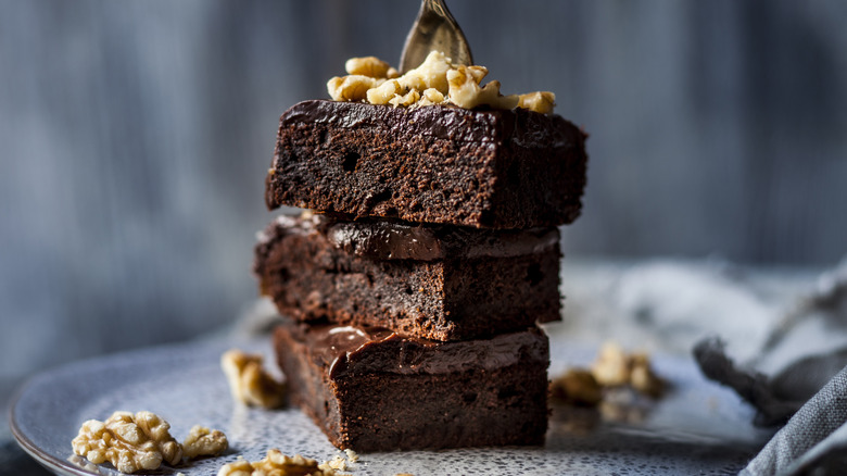 Someone stabs a fork into a plate stacked with brownies